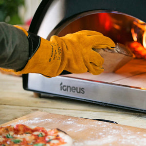 Another insitu image showing wood being placed into a pizza oven with the heat resistant gloves being used.