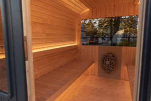 A photo taken from outside the black Lune Sauna showing the left side benches, heater and window.