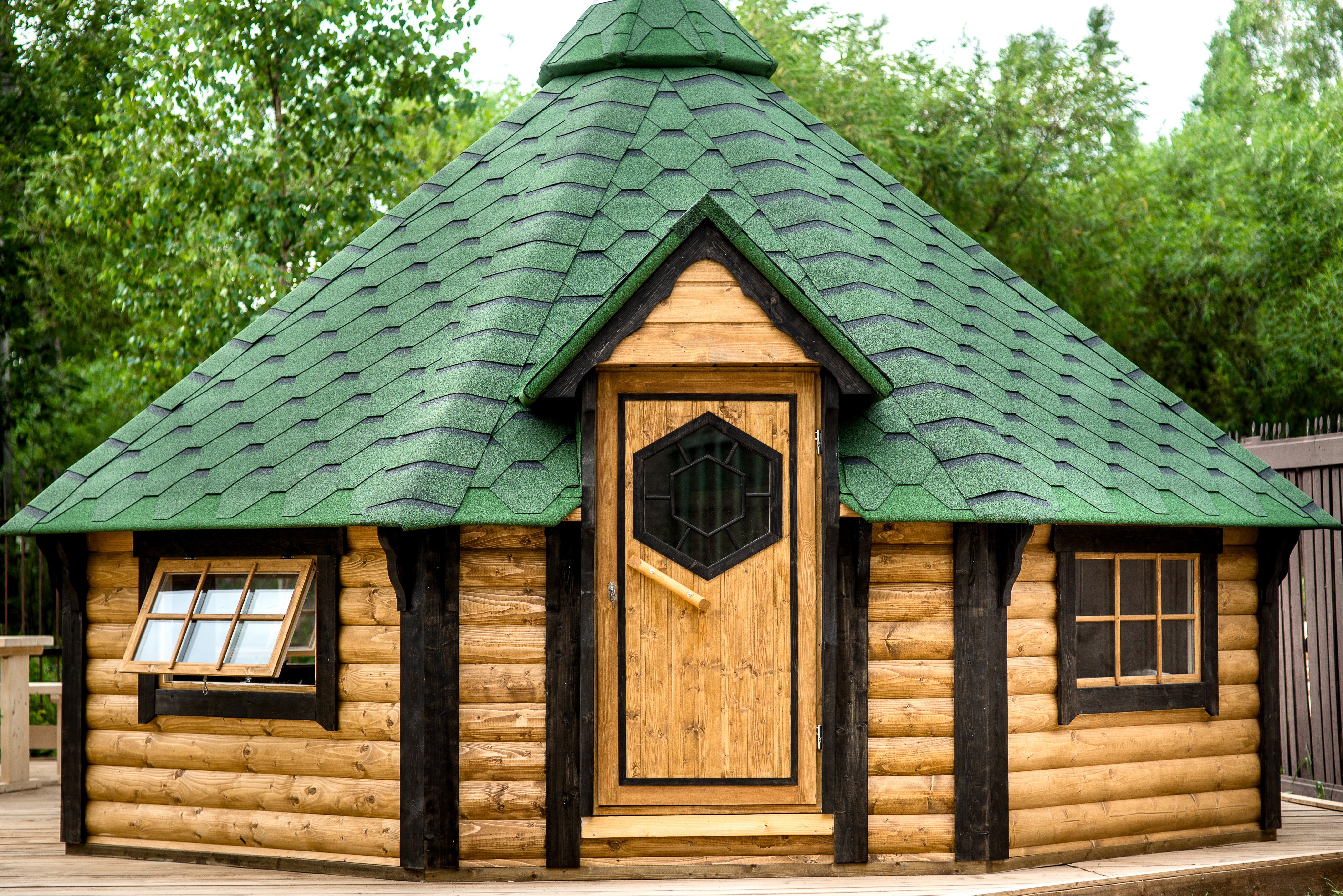 The exterior of the BBQ Hut in Light Oak (wood stain) with black accents and green shingle roof