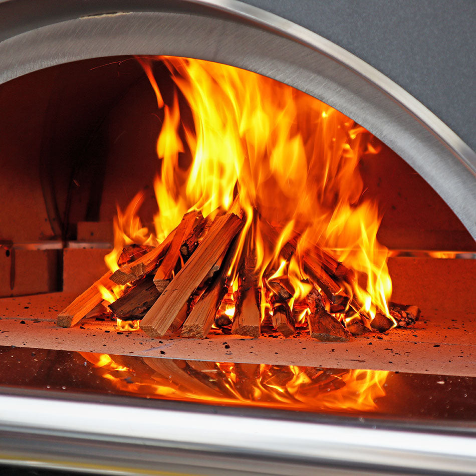 A close up shot on kindling burning inside of a woodfired pizza oven.