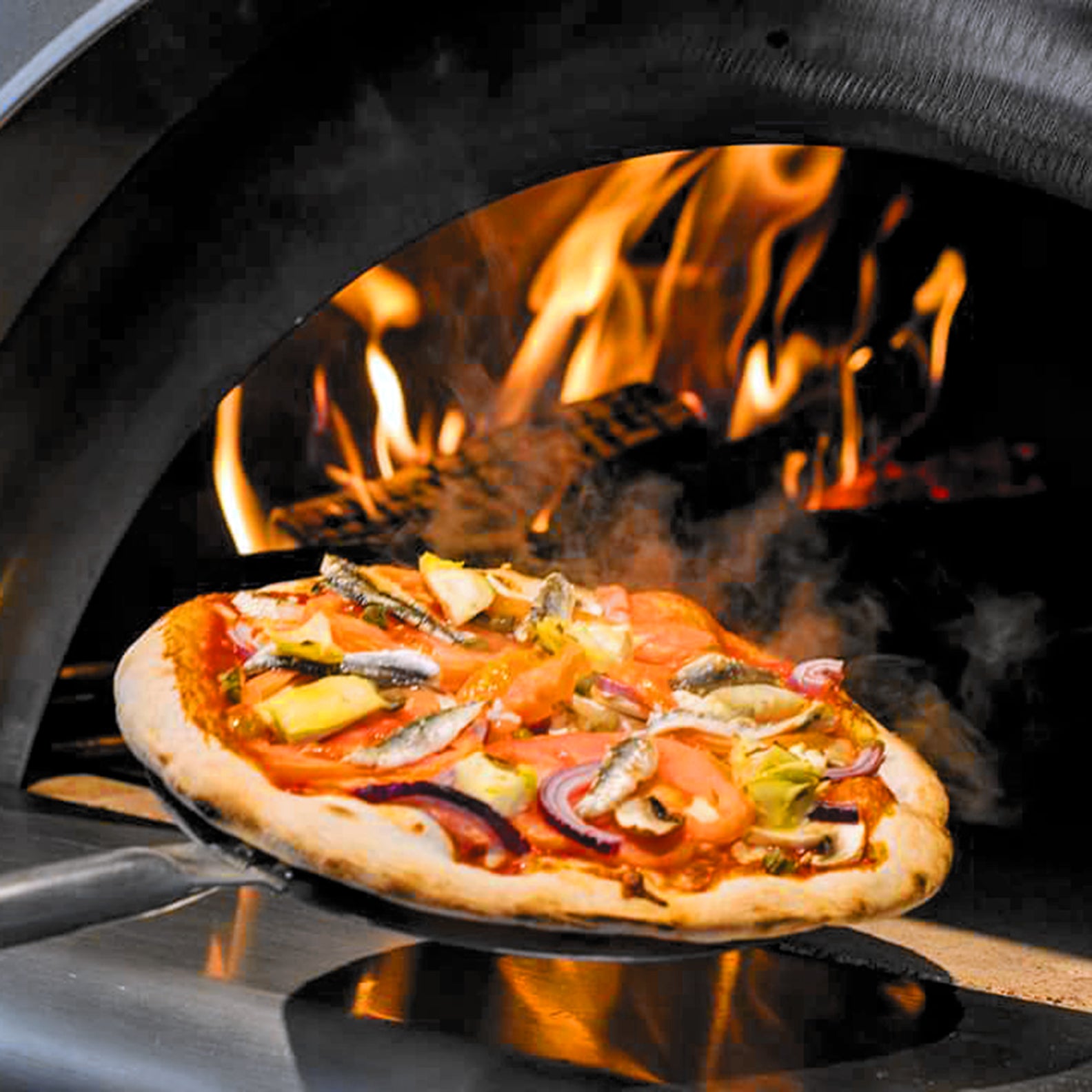 A pizza being removed from a lit woodfired pizza oven.