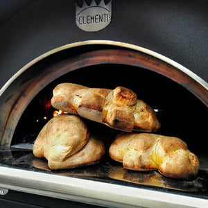 Some baked bread on the edge of a woodfired pizza oven.