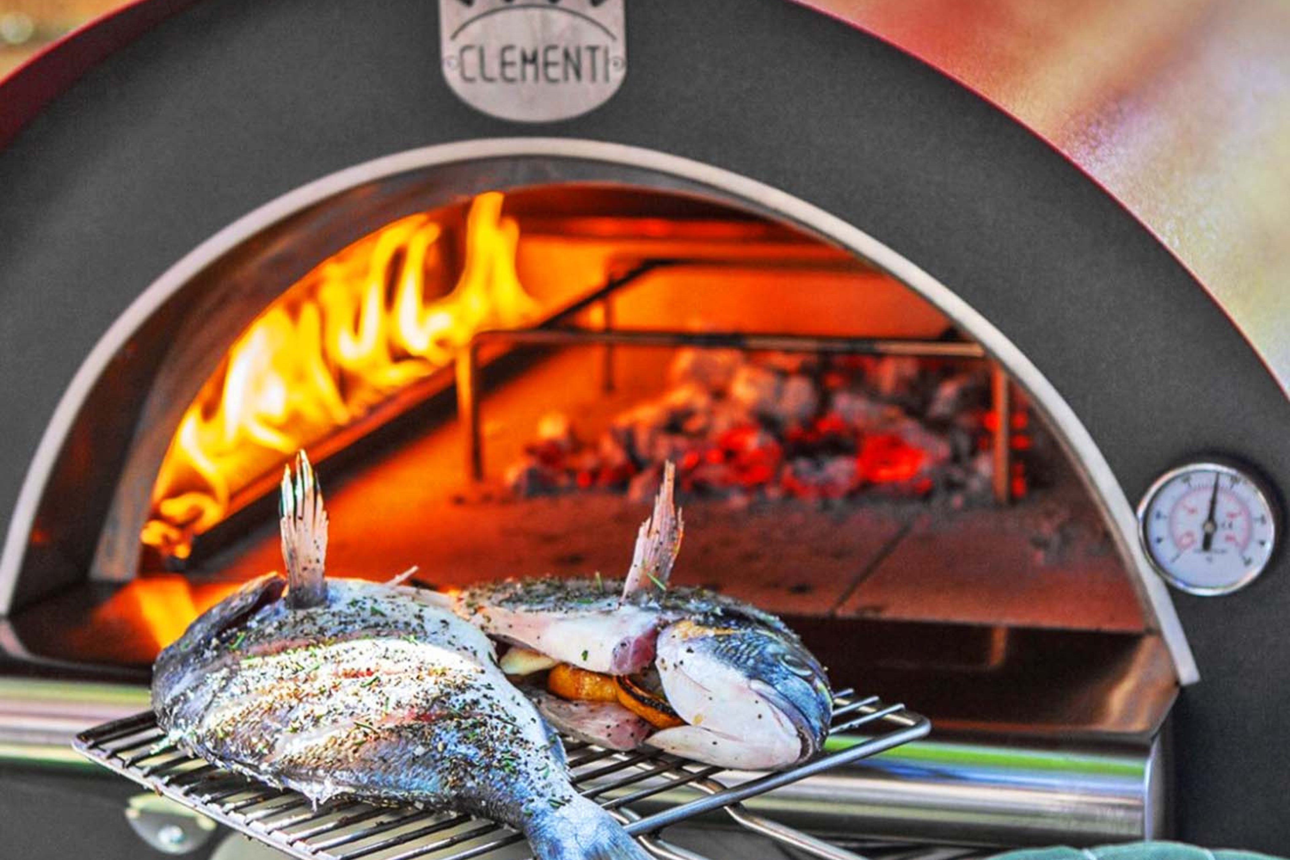 Some well seasoned, filled, filleted fish being placed into the gas fired pizza oven.