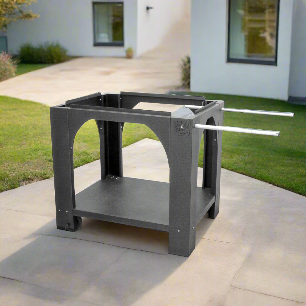 A black metallic pizza oven stand with two white handles for ease of moving in a modern garden.