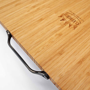 A close up shot of the Clementi Pizza Oven bamboo chopping board and the black carrying handle on a white background