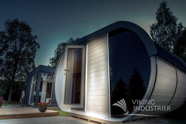 The Delight sauna atop a wooden terrace on a starry night with exterior lights turned on