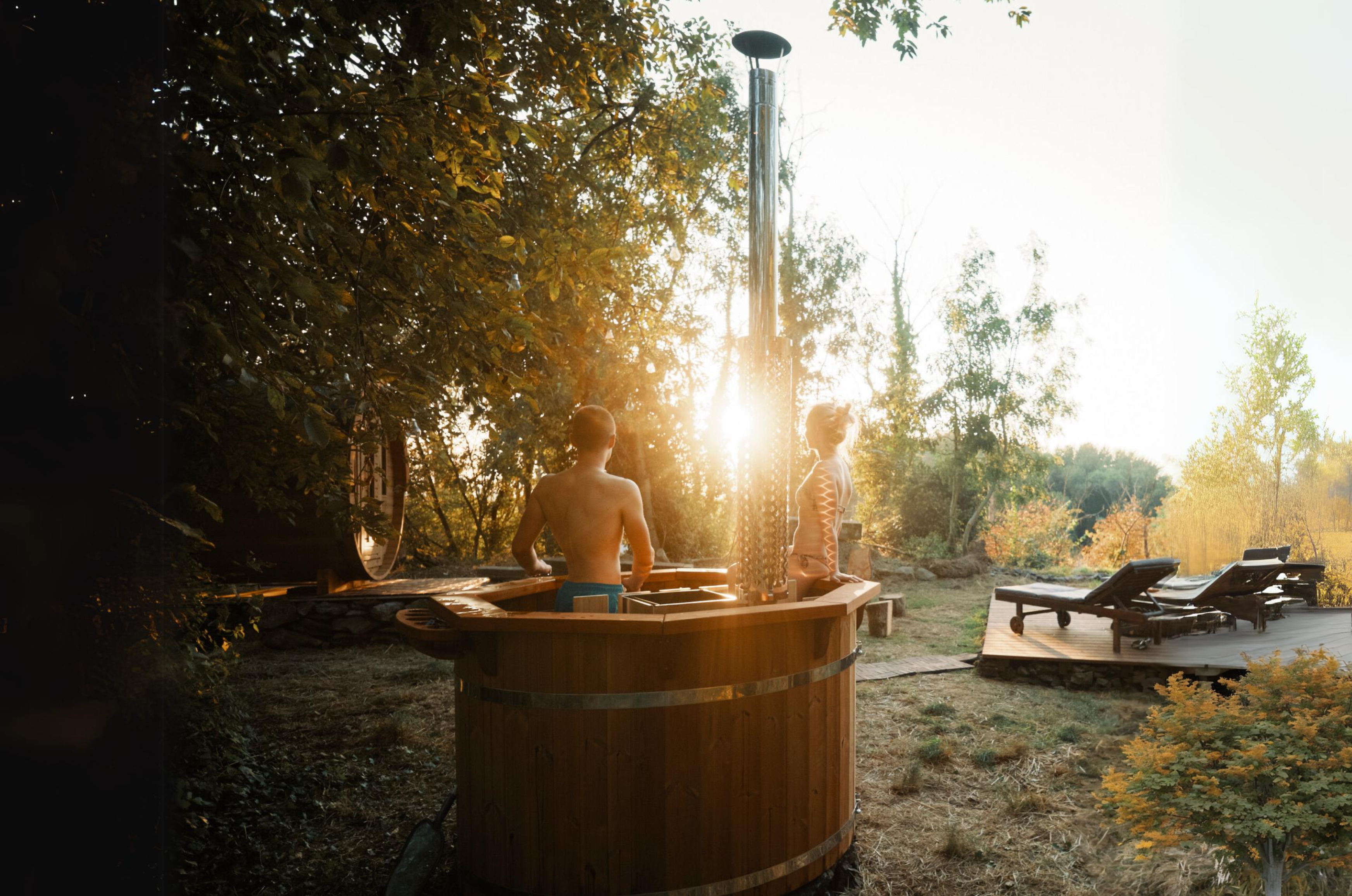 A lovely sun set with two people enjoying the 10 person hot tub, sauna and terrace in the background.