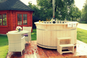 A light oak finish on a hot tub sat on a wooden terrace with a table and chairs.