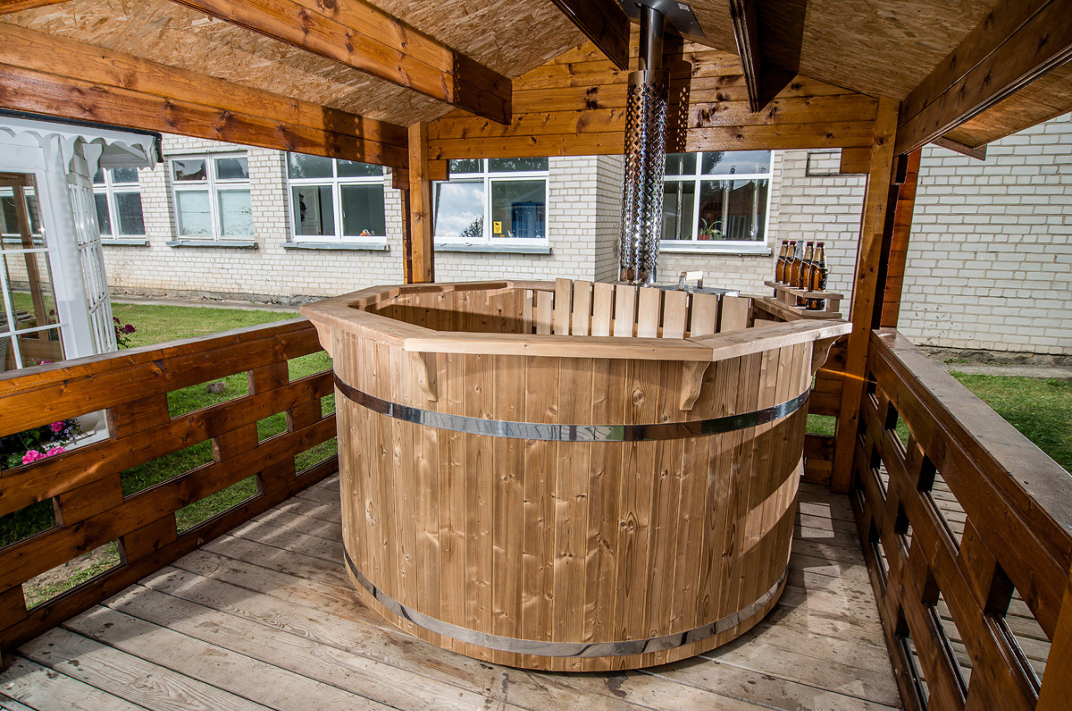 A 8 person hot tub sat inside a wooden structure with ventilation for the wood burning heater.