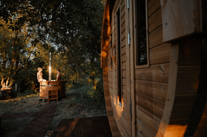 a long distance image showing the 8 person hot tub in a lovely garden with trees in the background and a sauna close up to our right.