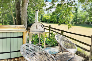 The Bambino garden pizza oven on the Bambino stand atop a wooden terrace  with garden furniture