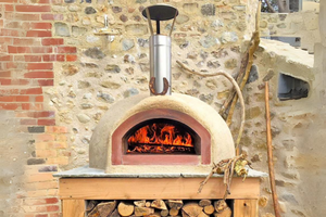 The Ceramiko Pro 1000wood fired pizza oven outdoor in an alcove with stone walls