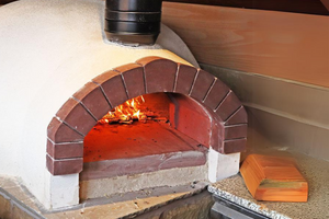 The Ceramiko Pro 1200 wood fired pizza oven outdoor atop a stone counter