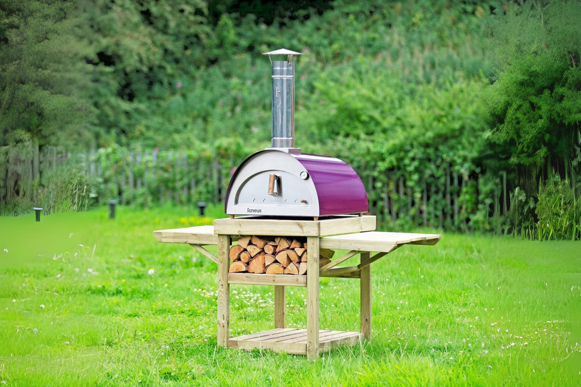 The Classico bbq pizza oven, in aubergine, atop the classico stand in a green field