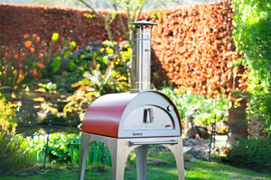 The Classico wood fired pizza oven exterior in antique-copper in a cozy garden