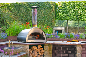 The Classico bbq pizza oven outdoor in a modern, floral garden