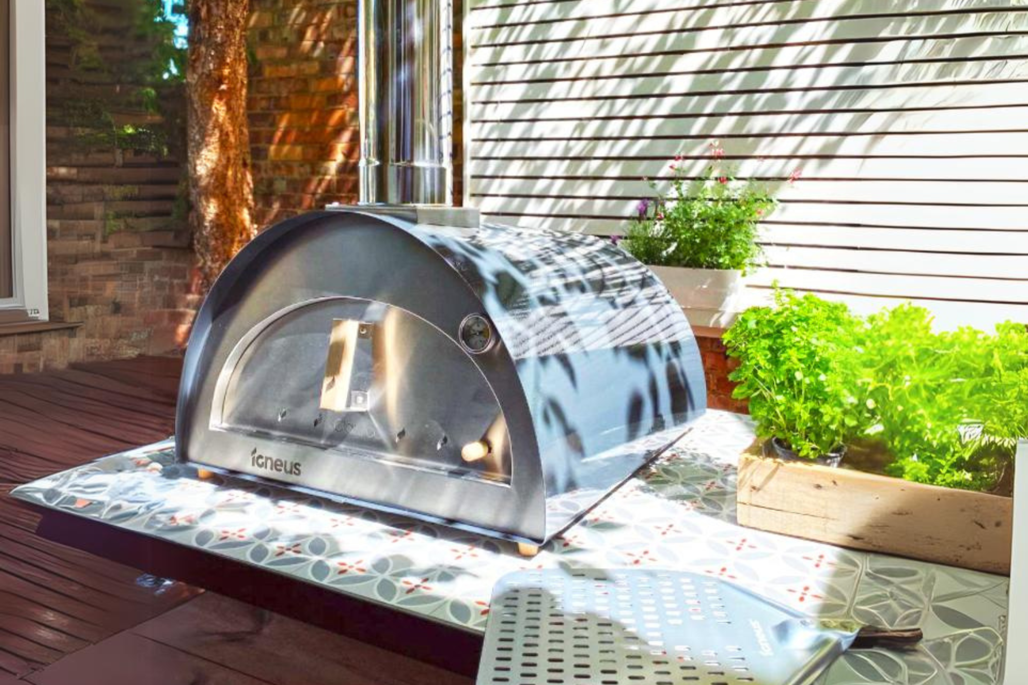 The Classico outdoor pizza oven exterior in graphite sitting on a table in a shady garden patio