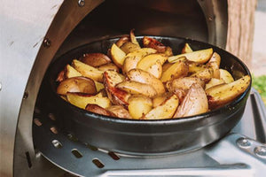 A close up of a bowl of Mediterranean vegetables cooking in the Minimo garden pizza oven 