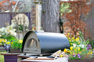 The Pro 600 outdoor pizza oven nestled in flowers in a quaint garden