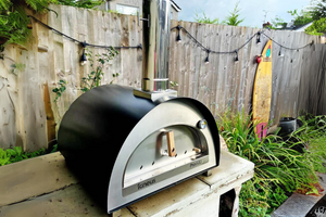 The Pro 600 outdoor pizza oven on a stone worktop in a standard garden.