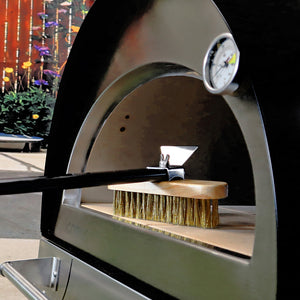 A side profile shot of the brush on the firebricks inside of an unlit igneus pizza oven outdoor