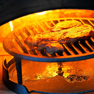 A steak is cooking well inside a lit BBQ pizza oven onto of the tuscan grill