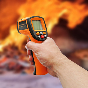 A close up shot of the digital thermometer being held with a pizza oven in a blurred background.