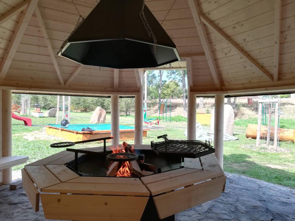 An image of the open BBQ hut from the inside facing out - the viking grill lit at the front ready to cook food with the grill hood above it.