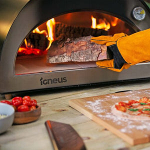 A piece of wood being put into a lit pizza oven