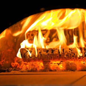 The logs from the pizza oven wood bundle being show inside of a BBQ pizza oven and they are lit.