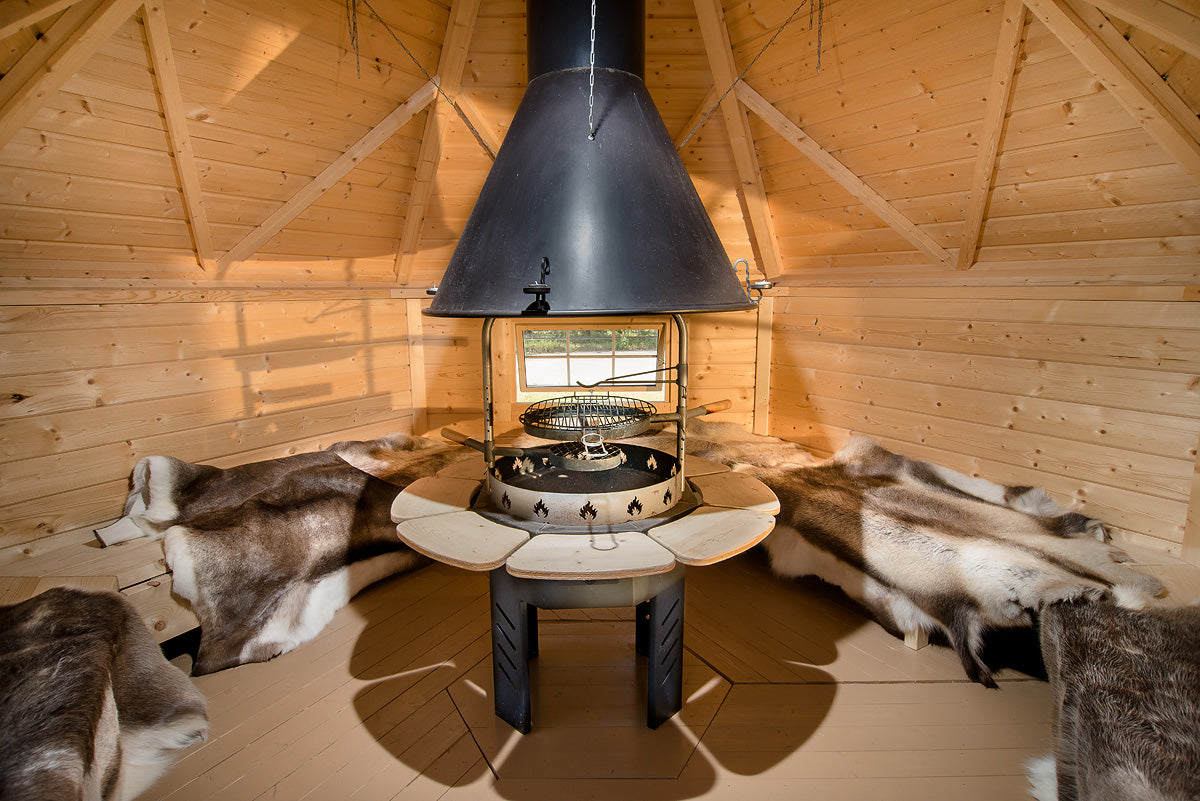 Inside of a Viking BBQ hut with reindeer hides all along the benches that encircle the cabin.