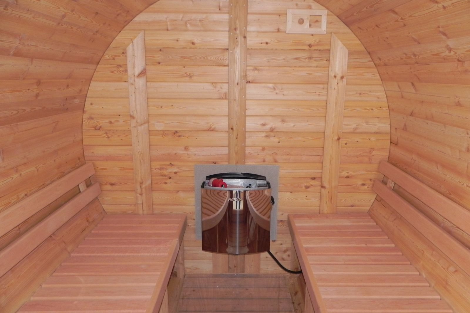 the interior of a sauna barrel showing the Harvia heater and the seating inside comfortable enough for 4 people.