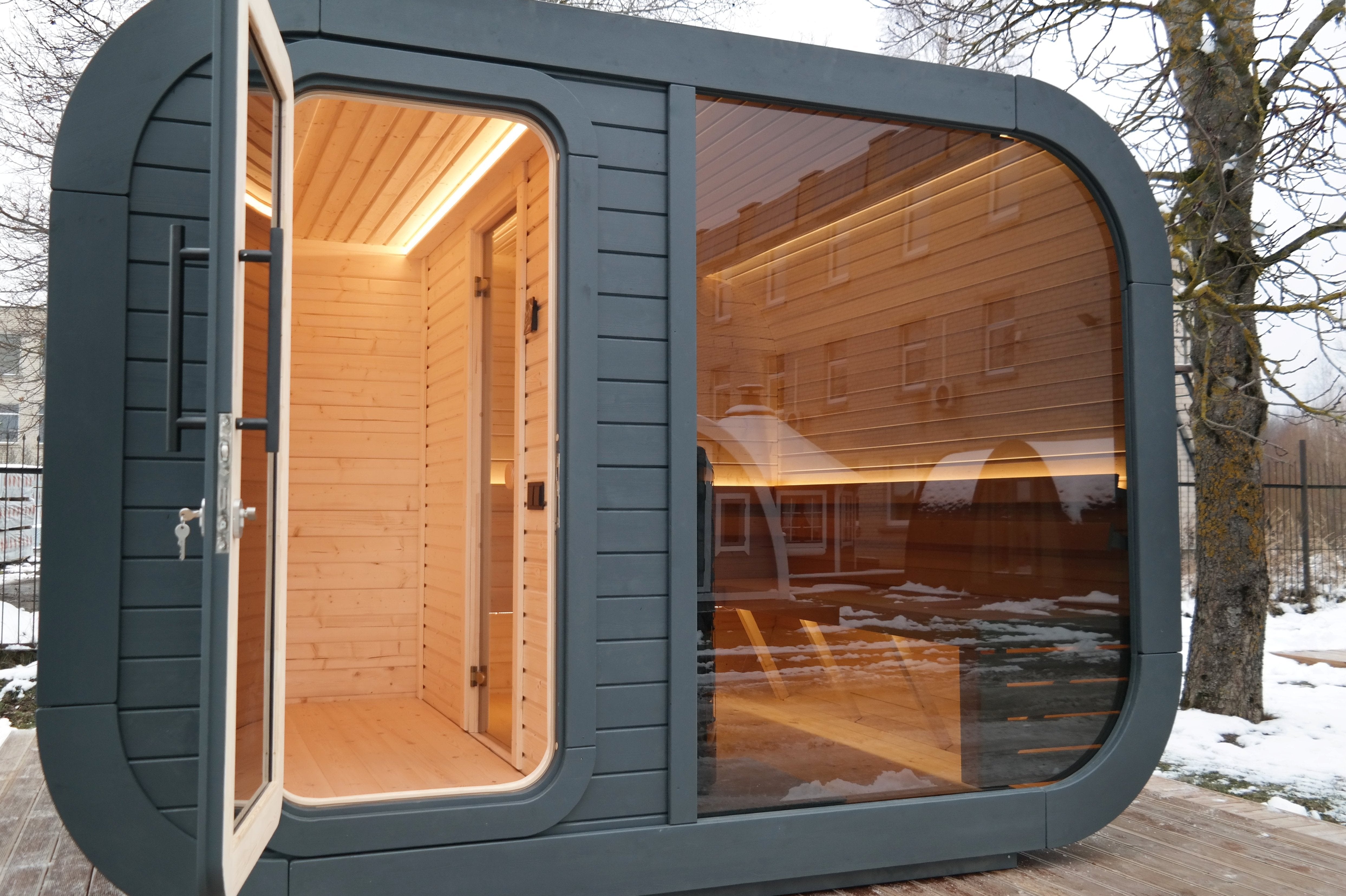 a close up shot or the Sauna with changing room - the door is open the interior lights are on and there is a large glass viewing window on the side of the cabin.