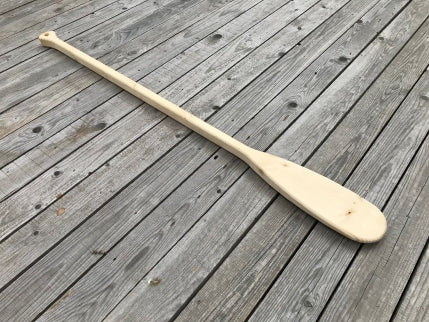 The spruce wooden paddle is laid down on a wooden terrace.