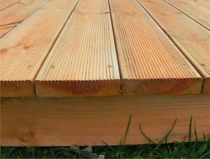 A close up image of the wooden terrace atop some grass.